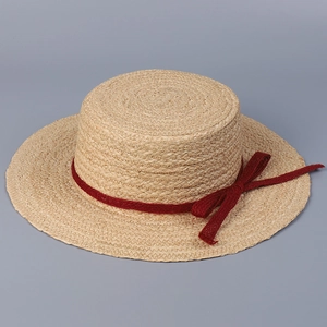 Detailed top view of a flat top raffia sun hat with a deep red bow and woven texture