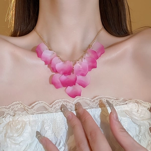 Close-up of pink gradient petal tassels and gold chain necklace on a model's collarbone