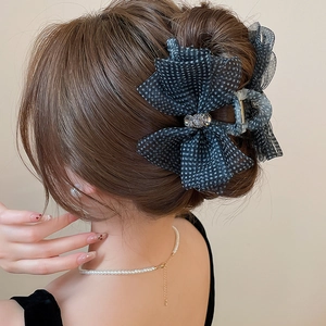 Detailed view of polka dot mesh bow hair claw clip with rhinestones on model's hair