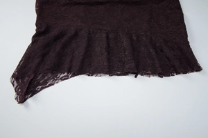 Détail d'une robe en dentelle violet foncé avec motifs floraux et ourlet festonné