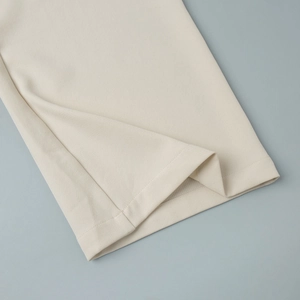 Detail shot of the hem of off-white wide-leg trousers showing neat stitching and texture
