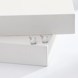 Macro shot of S925 sterling silver opal stud earrings on minimalist white geometric props