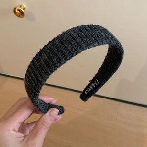 Détail de la texture d'un serre-tête tricoté gris foncé avec étiquette EMdrea à l'intérieur