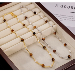 Detail of 925 silver tiger eye and pearl necklaces in gold and silver finishes