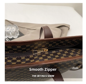 Detail shot of the golden metal zipper and brown vintage printed tote bag surface
