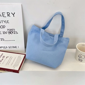 Detail of light blue canvas tote bag with sturdy handles on a minimalist shelf