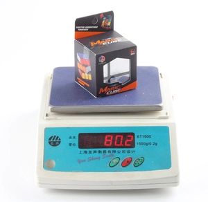 Detail showing the Magic Cube packaging on a digital scale weighing 80.2 grams