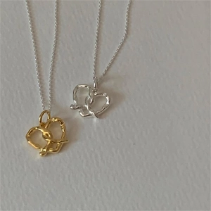 Detail of twisted heart necklaces in gold and silver finishes with fine metal chains