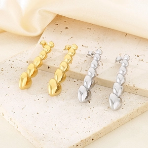 Close-up of polished gold and silver heart-shaped drop earrings on elegant background