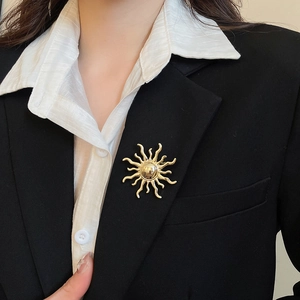 Detailed view of a golden sunburst brooch worn on a classic black suit lapel