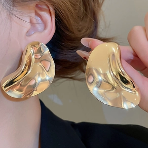 Detail showing wavy irregular gold metal texture earrings with a molten lava design