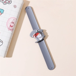 Detail view of a gray kids' shark slap watch with a silicone strap on a minimalist desk