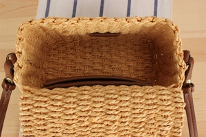 Detailed interior view of a woven straw crossbody bag with brown PU leather strap and lining