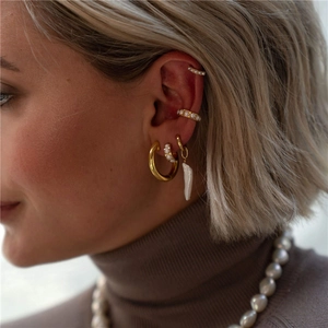 Detail view of model wearing gold hoop earrings and baroque pearl studs in French style