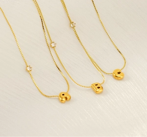 Detail of gold bubble letter A B C necklaces with zircon accents on a fine chain