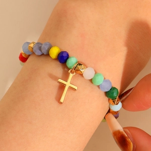 Colorful beaded bracelet with a gold cross pendant for women on wrist close-up view