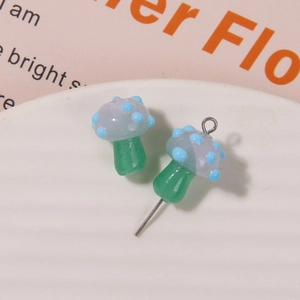 Detail of blue spotted mushroom charms on a white tray for handmade jewelry DIY