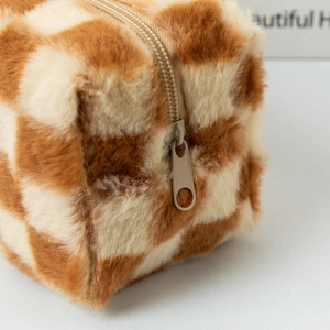 Dettaglio dell'astuccio in peluche a scacchi con cerniera marrone e trama morbida