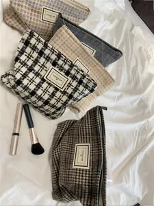 Macro shot of tweed plaid cosmetic bags with zip closure and fabric label detail