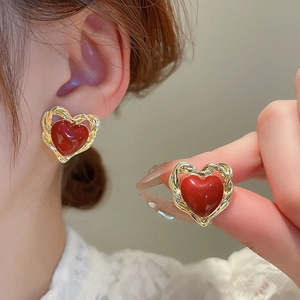 Detail of vintage red heart stud earrings with twisted gold frame and glossy finish
