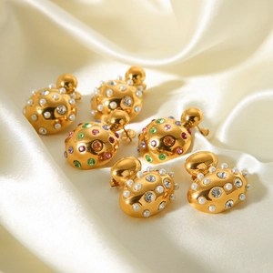 Close-up of gold-plated stud earrings with colorful crystals and pearls on white silk