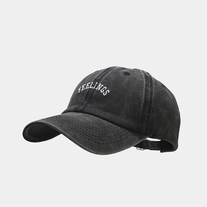 Detail of white FEELINGS embroidery on a vintage washed dark grey baseball cap