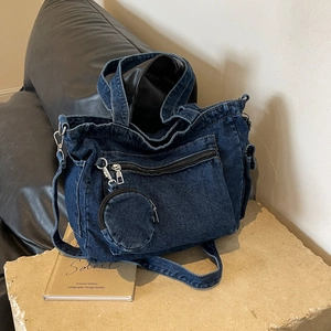 Blue denim tote bag with distressed finish and small round coin purse on stone base
