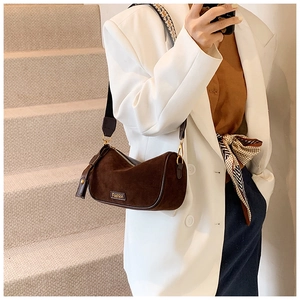 Detail of a brown suede Boston bag with a wide patterned strap and a golden zipper