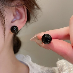 Detail of round black bead earrings worn on ear with premium gold plating finish
