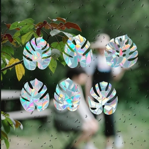 Detailed holographic monstera leaf window stickers showing rainbow prism effects on glass