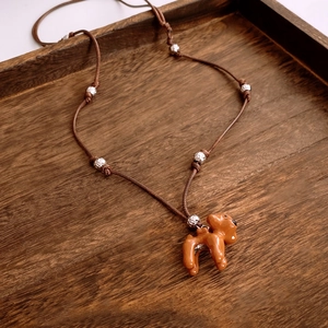 Détail du pendentif chiot rétro avec cordon marron réglable sur plateau en bois