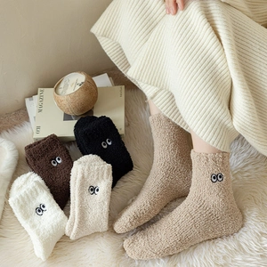 Close-up of cozy coral fleece socks with cute eye embroidery in warm home setting