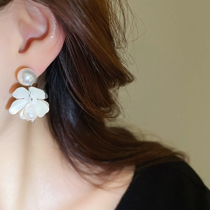 Close-up of model wearing floral pearl drop earrings with elegant baroque pearl details