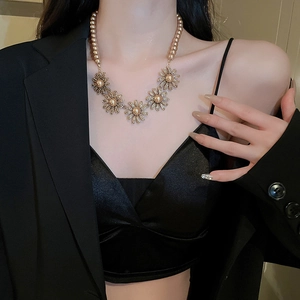 Detailed view of elegant gold daisy flower pearl necklace with sparkling rhinestones on model