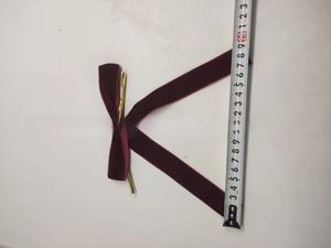 Burgundy velvet Christmas bow with gold metal tips measured by measuring tape