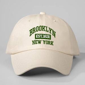 Detailed close-up of green Brooklyn embroidery on cream cotton twill baseball cap