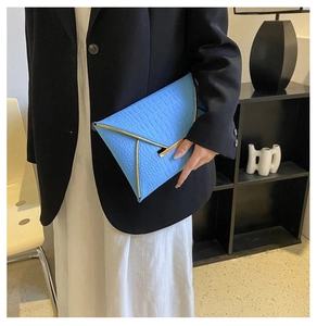 Détail de la pochette enveloppe bleue à motif crocodile avec bordure métallique dorée