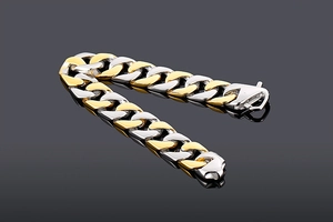 Detail of two-tone gold and silver stainless steel Cuban link bracelet on dark background