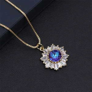 Detailed macro view of a gold sunflower pendant with a deep blue sapphire-like center stone