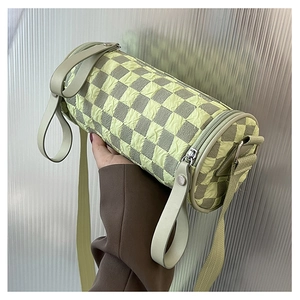 Detail of cylinder bag with green checkerboard bubble texture and wide shoulder strap