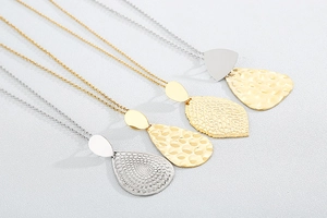 Detailed view of gold and silver plated leaf and water drop pendants with hammered texture