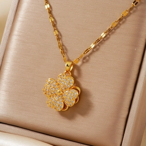 Golden flower pendant necklace with clear zircon stones displayed in a beige velvet jewelry box