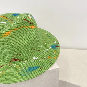 Detail of hand-painted graffiti design on green straw fedora with colorful paint splashes