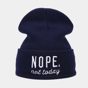 Close-up of dark blue knit beanie featuring white NOPE. not today embroidery detail
