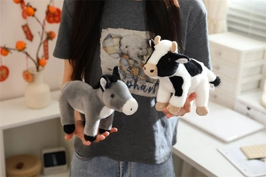 Hand holding soft plush donkey and cow animal dolls in a cozy home setting