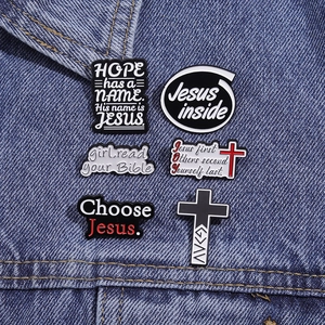 Detailed view of six religious enamel pins styled on a blue denim jacket pocket