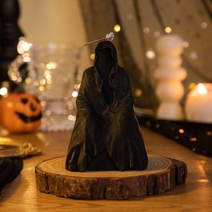 Macro detail of a black hooded grim reaper candle on a wooden base for Halloween