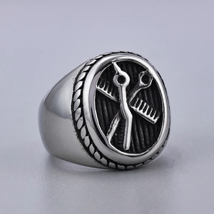 Macro view of vintage silver barber ring featuring crossed scissors and comb pattern