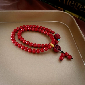 Détail macro du bracelet en perles de cinabre rouge avec breloque éléphant dorée