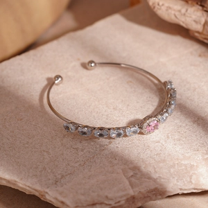 Detail of silver C-shaped cuff bracelet with oval blue and pink zircons on stone